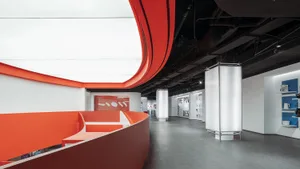 Modern office lounge area with red walls, concrete flooring, and curved architectural elements.