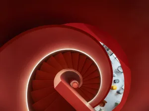 A modern red spiral staircase viewed from above.