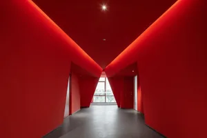 A red corridor with geometric shapes and ceiling lights.