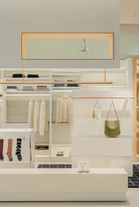 A clothing retail store with neutral-toned decor, featuring shelves and hanging garments.