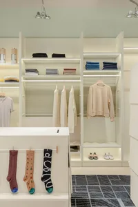 A stylish and organized minimalist fashion closet with white shelves and steel hangers.
