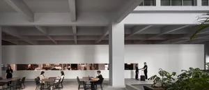A minimalist co-working space featuring concrete and glass elements.