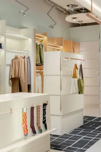 A modern fashion store featuring white rail shelves and wooden hangers.