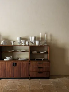 A modern interior setting featuring a wooden and ceramic display cabinet with white ceramic vases and plates.