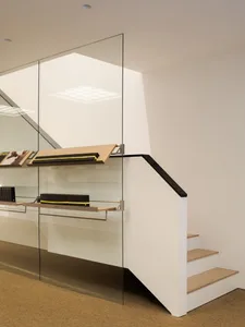 A modern staircase with glass walls and display shelves showing design objects.
