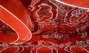Modern red interior space with curved walls and mirrored surfaces.