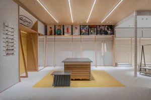Modern retail store interior with wooden counter, white walls, and yellow accents.