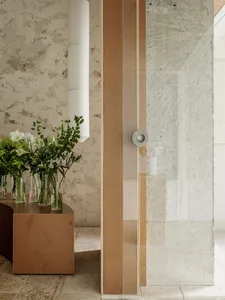 A modern interior design of a room with concrete walls and a wooden column, featuring a table with flower arrangements.