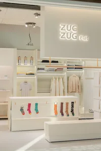 A retail store showcasing clothing on shelves and racks, with a minimalist design.