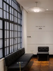 Modern spa interior with black leather furniture, large windows, and white walls.