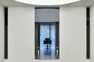 A minimalist waiting room with a glass entrance, showcasing sleek and modern design elements.