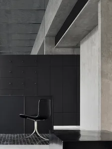 A modern storefront with concrete walls and a sleek, black chair.