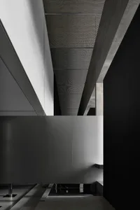 A minimalist, modern interior corridor with concrete walls and flooring, featuring a sleek, open design and a geometric ceili