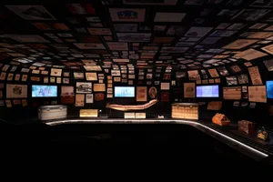 An exhibition showcasing a variety of design objects and materials, including trunks, bags, and photographs.