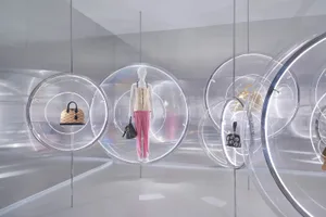 A minimalist retail display featuring clear plastic spheres containing fashion accessories and clothing.