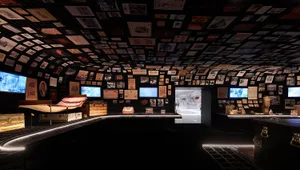 Various photographs and documents pinned to a ceiling in a museum exhibit setting.