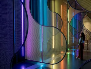 A woman standing in a space adorned with colorful lights and curved glass panels