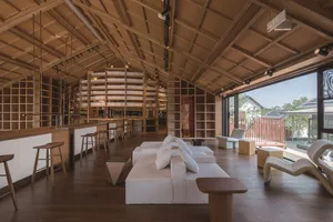 A restaurant with industrial design features, wooden furniture, and exposed beams on the ceiling.