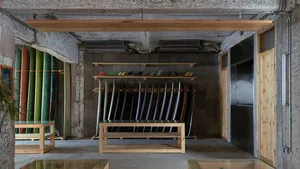 A minimalist indoor surf shop with wooden racks and concrete walls.