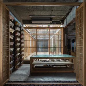 A minimalist restaurant interior with concrete floors, wooden walls, and a large glass window.