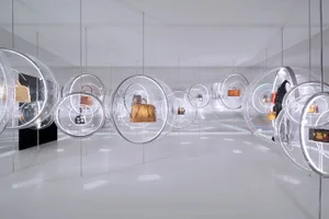 A minimalist retail display featuring glass spheres containing handbags.