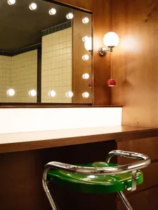 Modern bathroom with wooden counter, porcelain tiling, and round bulb lighting fixtures.