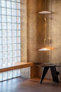 A modern coffee shop interior featuring wooden seating and glass blocks in the window.