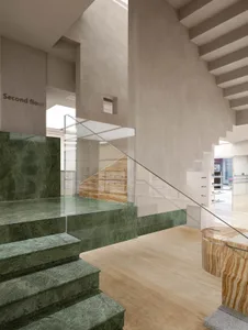 Modern marble staircase with glass railing and wooden floor.