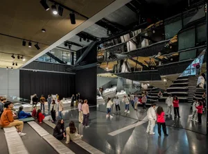 Visitors exploring a contemporary museum exhibition with reflective surfaces and geometric shapes.