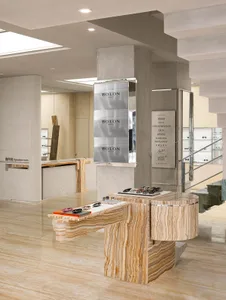 A modern optical retail store with a marble interior, featuring eyewear displays and a sleek, contemporary design.