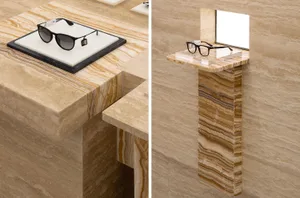 A stylish retail display featuring black sunglasses and a clear spectacle frame placed on a marble surface and pedestal.