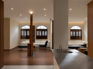 Modern minimalist living room with wooden floors, concrete accents, and large windows.