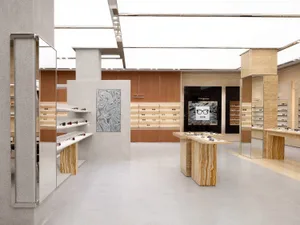A modern retail interior featuring a marble eyewear shop with wooden shelves and glass display cases.