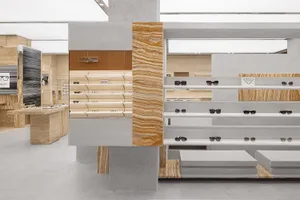 Modern retail store interior with marble shelves displaying sunglasses.