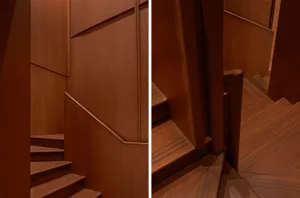 Detailed view of a wooden staircase with a wooden handrail and wall panels.