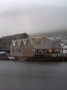 A modern industrial wooden building with a sloped roof and large glass windows.