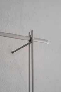 A minimalist metal clothing hanger mounted on a wall.