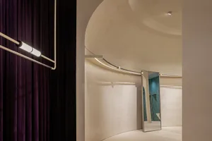 A modern clothing store interior featuring a velvet curtain, aluminium bar, and concrete wall.