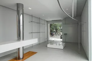 Modern minimalist retail shop interior with metal shelves, glass display cases, and concrete floor.