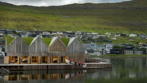 Modern wooden architectural design with a grass-covered hillside in the background.