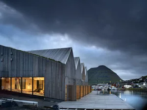 A modern wooden structure with a slanted roof and large windows.