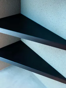 Modern floating shelves made of concrete against a textured blue wall