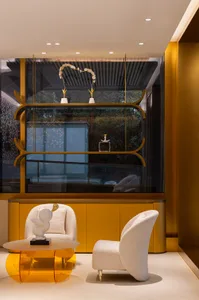 A modern living room features glass walls, wood accents, and fabric furniture.