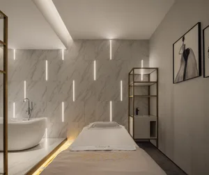 A luxurious beauty spa treatment room featuring modern marble design and a single treatment bed.