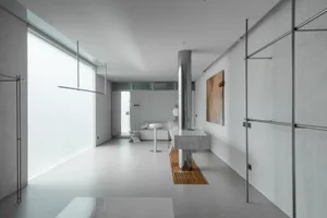 A minimalist living room with concrete walls, metal accents, and a glass column.