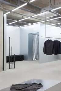 Modern retail store with minimalist design, featuring concrete walls and a metal counter.