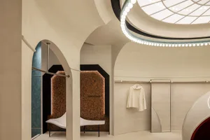 A modern retail store with concrete walls and ceiling, featuring a clothing rack with minimalist white clothes.