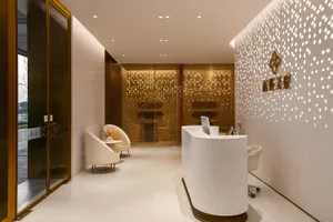 Modern interior design featuring a sleek, white marble reception desk, white armchairs with yellow accents, and a glass wall 