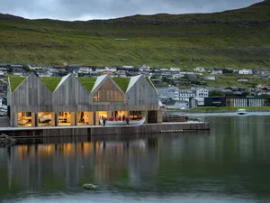 Modern boat harbour facility featuring timber and green roof amidst serene waters and scenic surroundings.