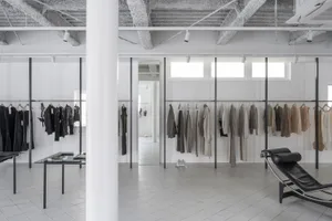 An industrial-style clothing store featuring minimalist design elements, metal clothing racks, concrete floor, and glass disp